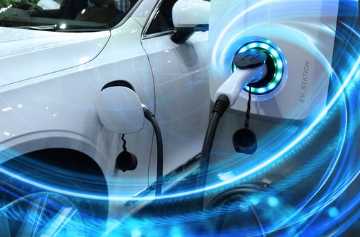 EV_Car_or_Electric_vehicle_at_charging_station_with_the_power_cable_supply_plugged_in_on_blurred_nature_with_blue_enegy_power_effect.-1